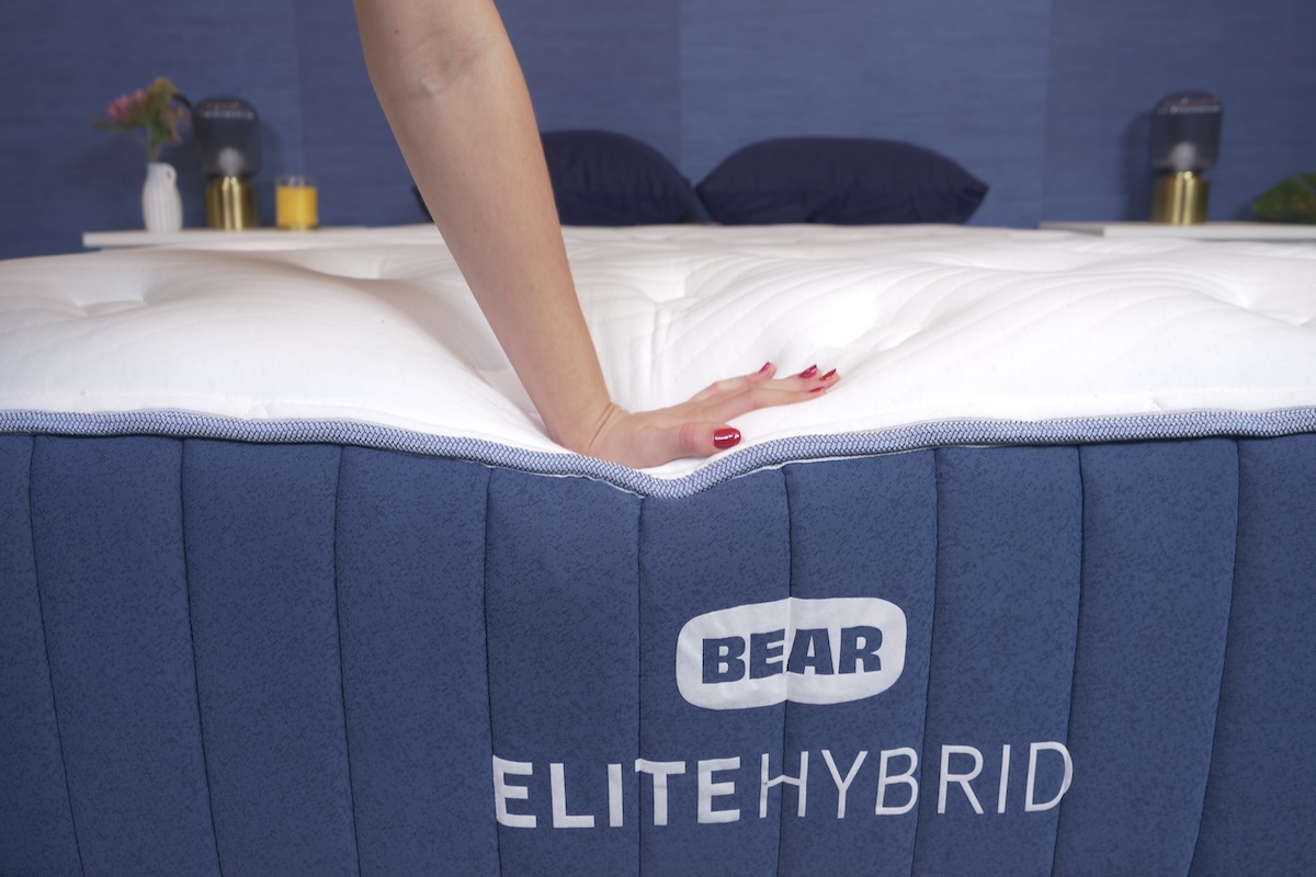 Hand pressing down on the edge of the Bear Elite Hybrid