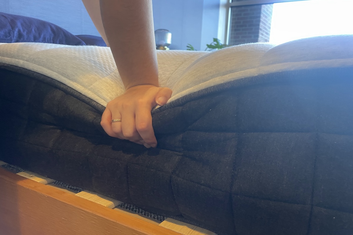 Tester pushing on the edge of a Helix mattress