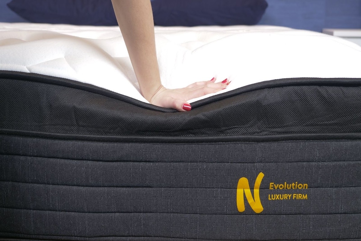 Hand pushing down on edge of Nolah Evolution mattress
