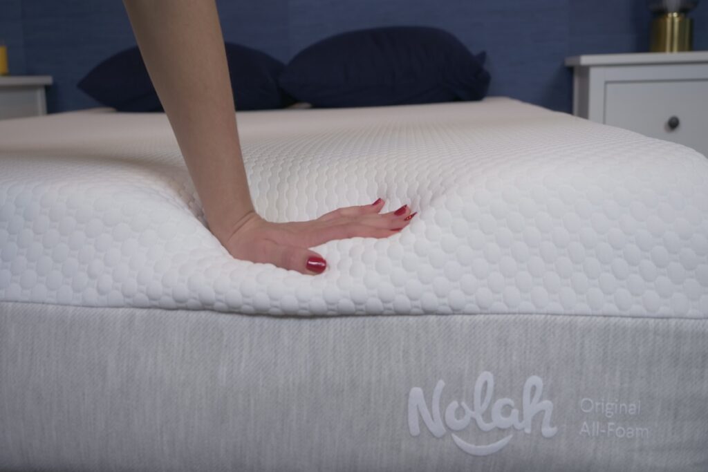 Hand pressing down on the Nolah Original Hybrid