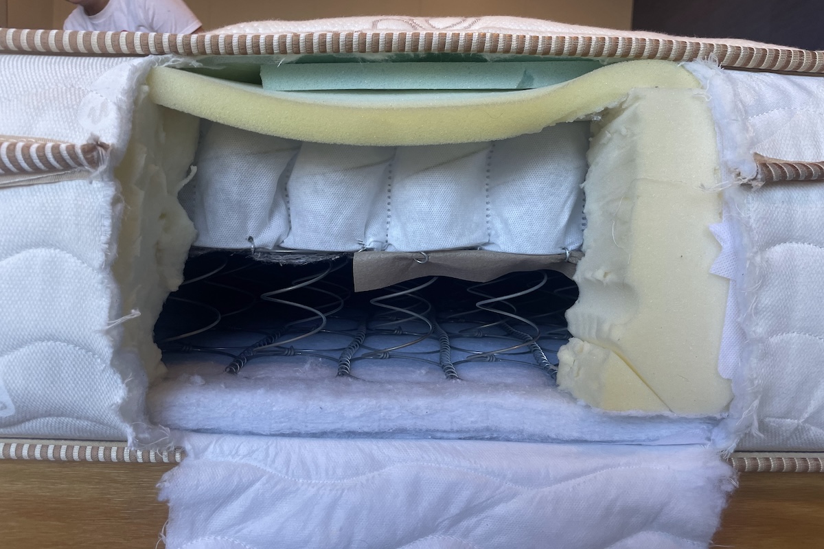  The side of a Saatva Classic mattress with a rectangle cut out showing the interior of the mattress